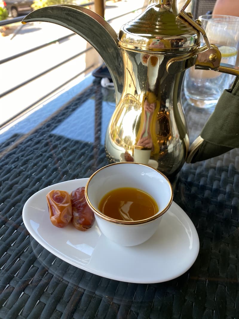 šálka čerstvej arabskej kávy podávana s dubajskými datlami doplňa kanvička na kávu nazývana Dallah
