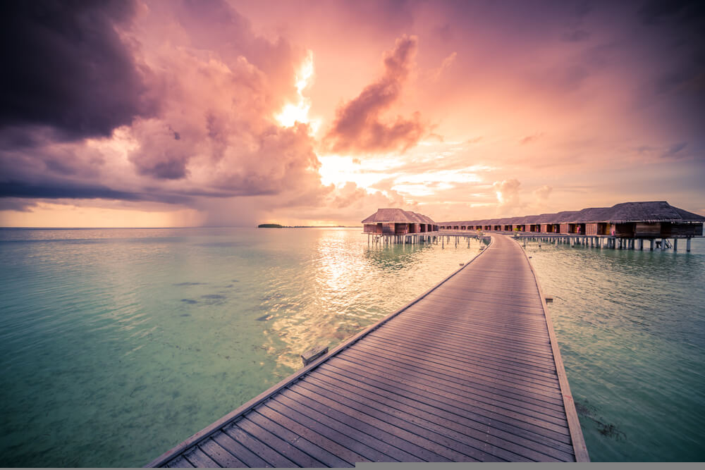 Zamračená obloha s prenikajúcim slnkom počas obdobia dažďa na Maldivách s výhľadom na more